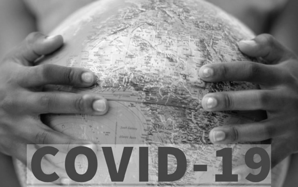 Kaksi kättä pitelee karttapalloa, jossa näkyvillä Afrikan manner. Kuvassa myös teksti Covid-19.